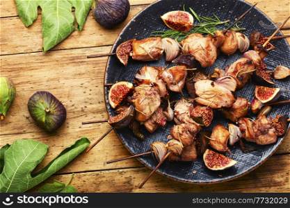 Fried chicken meat on skewers.Chicken kebab with figs on rustic wooden surface. BBQ with chicken and figs