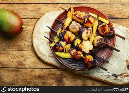 Fried chicken meat on wooden skewers. Shashlik with mango. Chicken breast kebab with mango