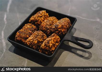 Fried chicken meatballs in a black plate on a marble background
