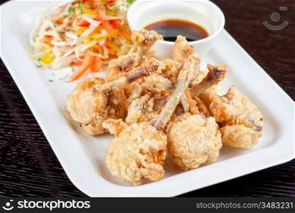 Fried chicken wings garnished with fresh vegetables with Teriyaki sauce