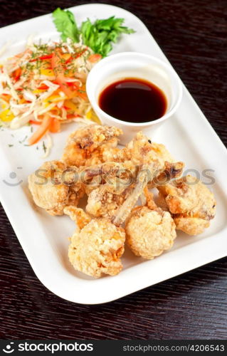 Fried chicken wings garnished with fresh vegetables with Teriyaki sauce