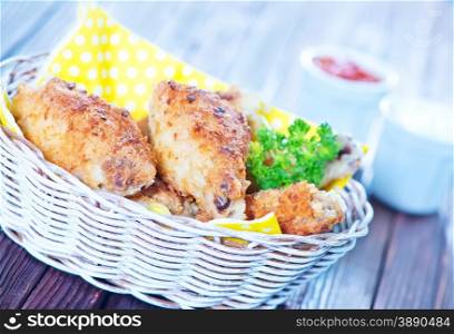 fried chicken wings in basket and on a table
