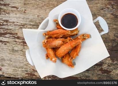 fried chicken wings with sauce thai food on wooden table food background - top view  