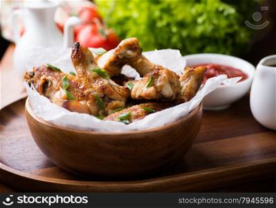Fried chicken wings with sauces in wooden bowl, selective focus