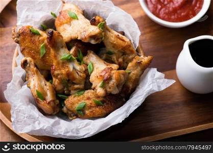 Fried chicken wings with sauces in wooden bowl, top view