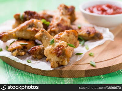 Fried chicken wings with sauces on wooden board, close up, selective focus