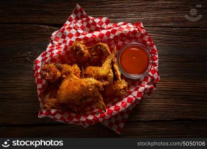Fried chicken with sauce and spices on wooden table