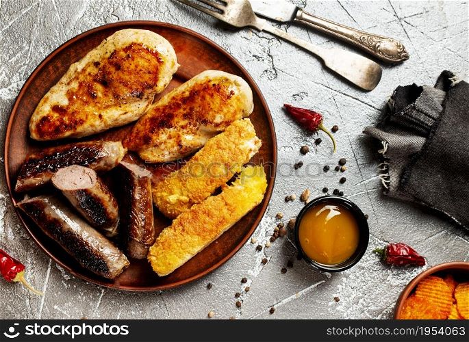 Fried chicken with sausages and white fish on plate