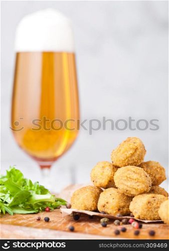 Fried crispy chicken popcorn with fresh salad and glass of beer on chopping board on wooden background