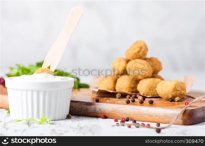 Fried crispy chicken popcorn with fresh salad and sauce on chopping board on wooden background