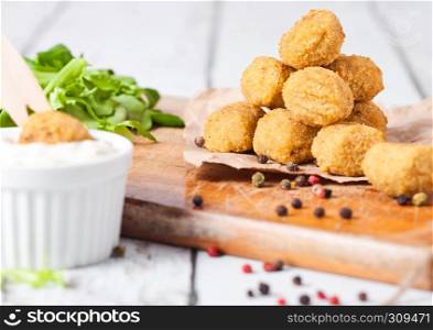 Fried crispy chicken popcorn with fresh salad and sauce on chopping board on wooden background