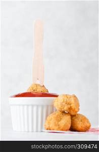 Fried crispy chicken popcorn with ketchup and wooden fork stick on marble background