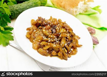 Fried cucumbers with garlic, honey, soy sauce and spices in a plate, bread, kitchen towel and parsley on a wooden board background