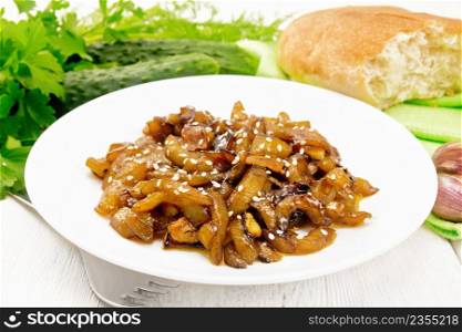 Fried cucumbers with garlic, honey, soy sauce and spices in a plate, bread, napkin and parsley on a white wooden board background