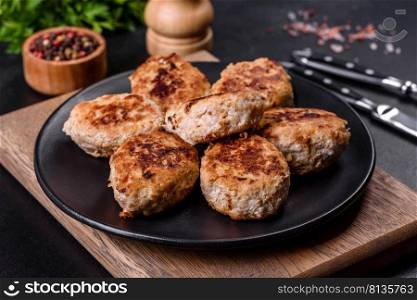 Fried cutlets from minced meat in frying pan and spices on a dark concrete background. Delicious fresh fried minced meat patties on a dark concrete background