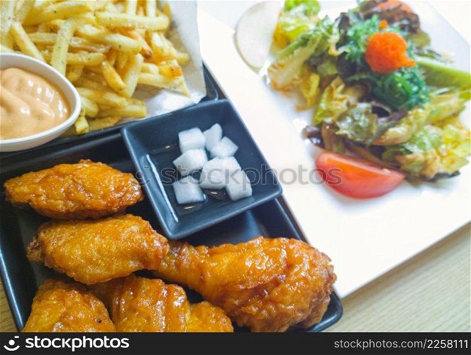 Fried drumsticks with french fries on wooden table top 