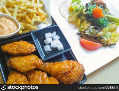 Fried drumsticks with french fries on wooden table top 