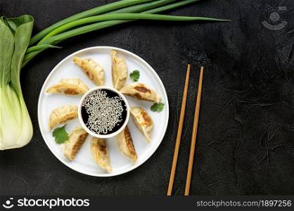 Fried dumplings gyoza with soy sauce, and chopsticks, top view. Vegetarian recipe with bock choy and green onion