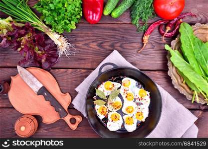 Fried egg and fresh vegetables and herbs on a wooden background, top view, empty space in the middle