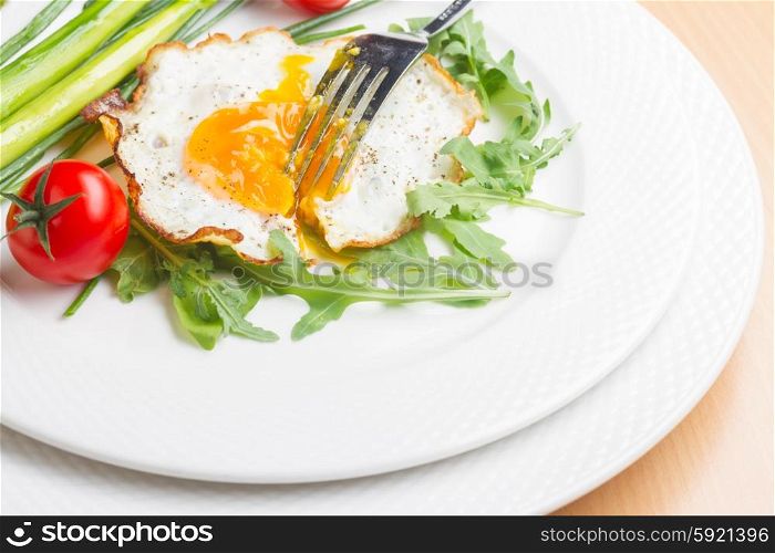 Fried egg. Fried egg with tomatoes and green salad on white plate