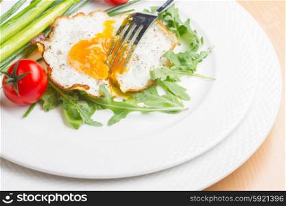 Fried egg. Fried egg with tomatoes and green salad on white plate