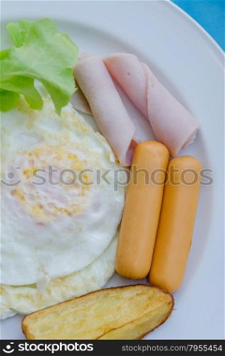 fried egg , ham , sausage and grilled potato on dish , fresh breakfast