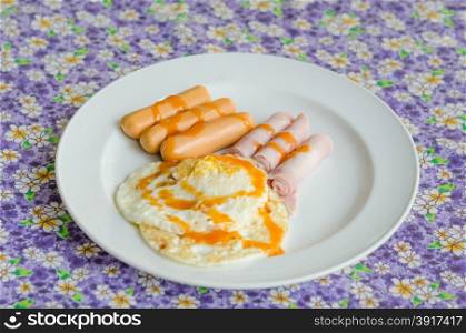 fried egg , ham , sausage with sauce on dish