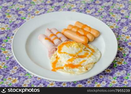 fried egg , ham , sausage with sauce on dish