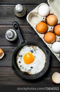 Fried egg in a frying pan. On a wooden background.. Fried egg in a frying pan