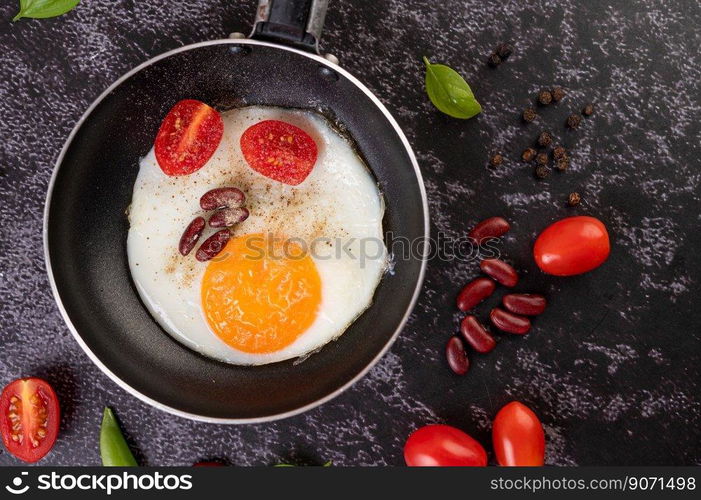 Fried egg in a pan with tomatoes and red beans.