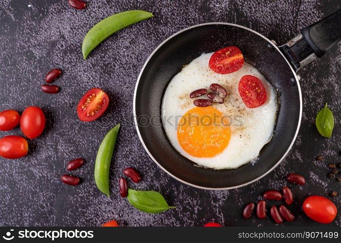 Fried egg in a pan with tomatoes and red beans.