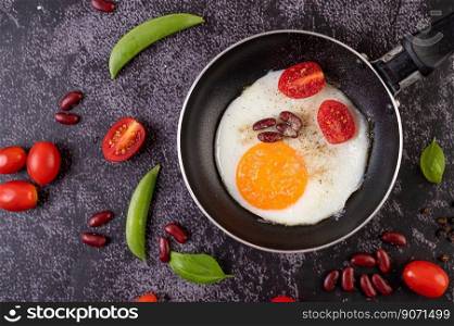 Fried egg in a pan with tomatoes and red beans.