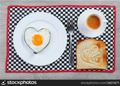 Fried egg in heart shape and toast with love message.Breakfast for a loved one