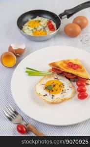 Fried egg on a white plate with toast, sliced ??Spring onion and sliced ??tomatoes