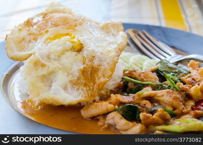 fried egg over rice and pork fried with chili pepper and sweet basil , curry sauce