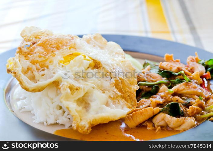 fried egg over rice and pork fried with chili pepper and sweet basil , curry sauce