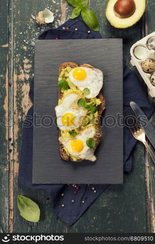 Fried egg sandwich: quail eggs, avocado and cheese on whole wheat bread