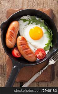 Fried egg sausages tomatoes in pan for breakfast