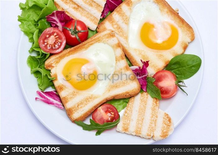 Fried egg Toasts with heart shaped holes on white ceramic plate.. Fried egg Toasts with heart shaped holes on white ceramic plate