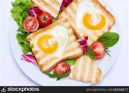 Fried egg Toasts with heart shaped holes on white ceramic plate.. Fried egg Toasts with heart shaped holes on white ceramic plate