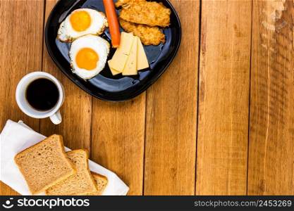 Fried egg, wholegrain toast, cheese, hotdog and cup of coffee for breakfast over wooden table, top view, copy space, breakfast concept