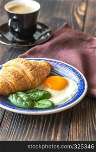 Fried egg with croissant and a cup of coffee