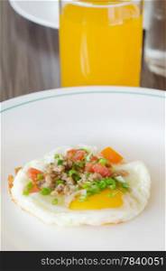 fried egg with minced pork and vegetable on white dish served with juice. egg and pork