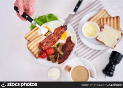Fried eggs, bacon, tomato, toasted bread in white ceramic plate and cup of coffee.. Fried eggs, bacon, tomato, toasted bread in white ceramic plate and cup of coffee