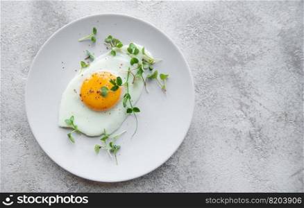 Fried eggs on a white plate on concrete background