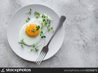 Fried eggs on a white plate on concrete background