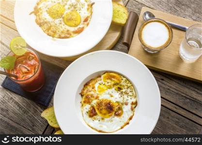 Fried eggs served on table with cappuccino coffee and mix fruits juice for breakfast