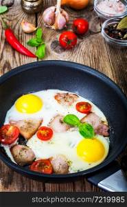 Fried eggs with bacon and tomatoes in a pan. Studio Photo. Fried eggs with bacon and tomatoes in a pan
