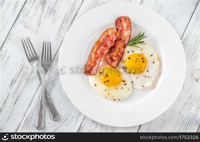 Fried eggs with bacon rashers  on the white plate