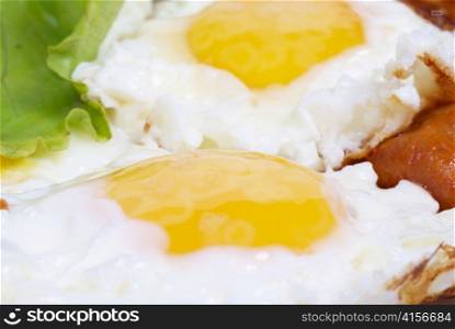 Fried eggs with meat and salad on the dish